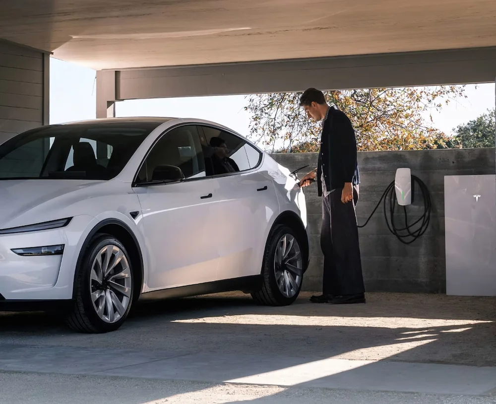 Person charging white electric car in garage.