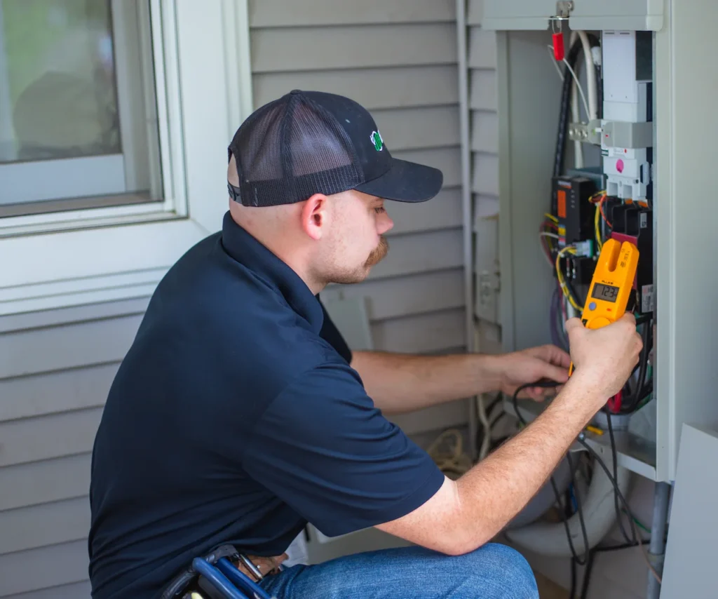 Electrician checking outdoor electrical panel with multimeter.