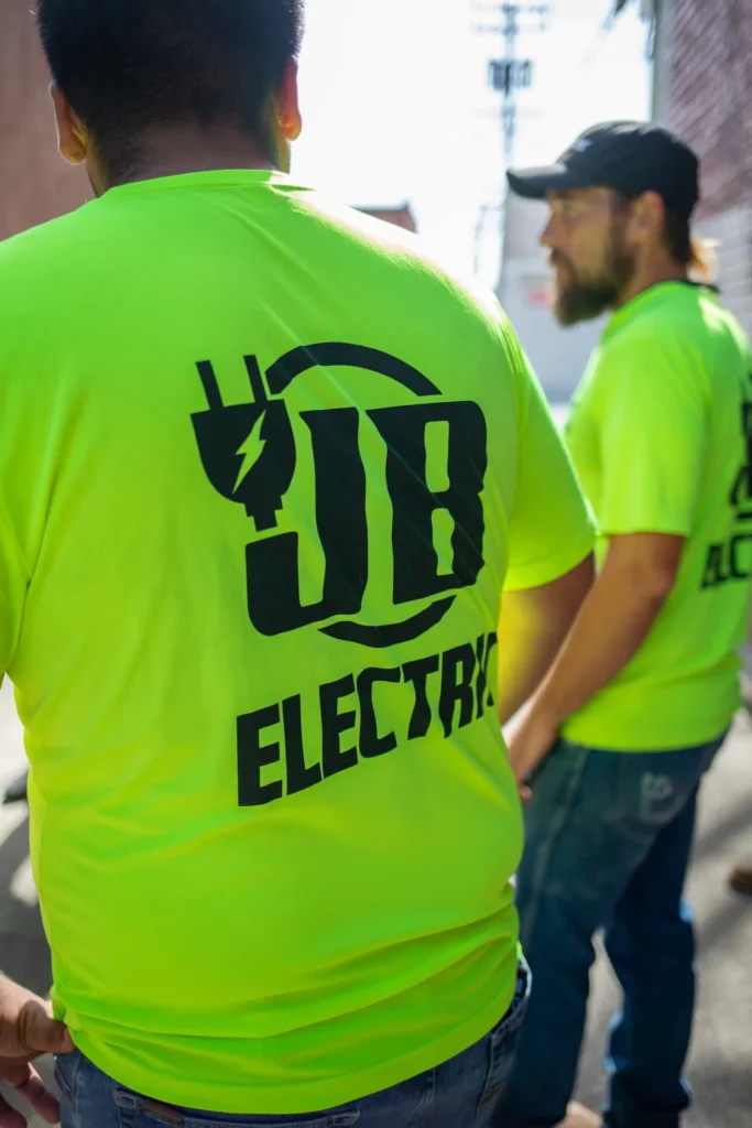 People wearing JB Electric neon shirts outdoors.