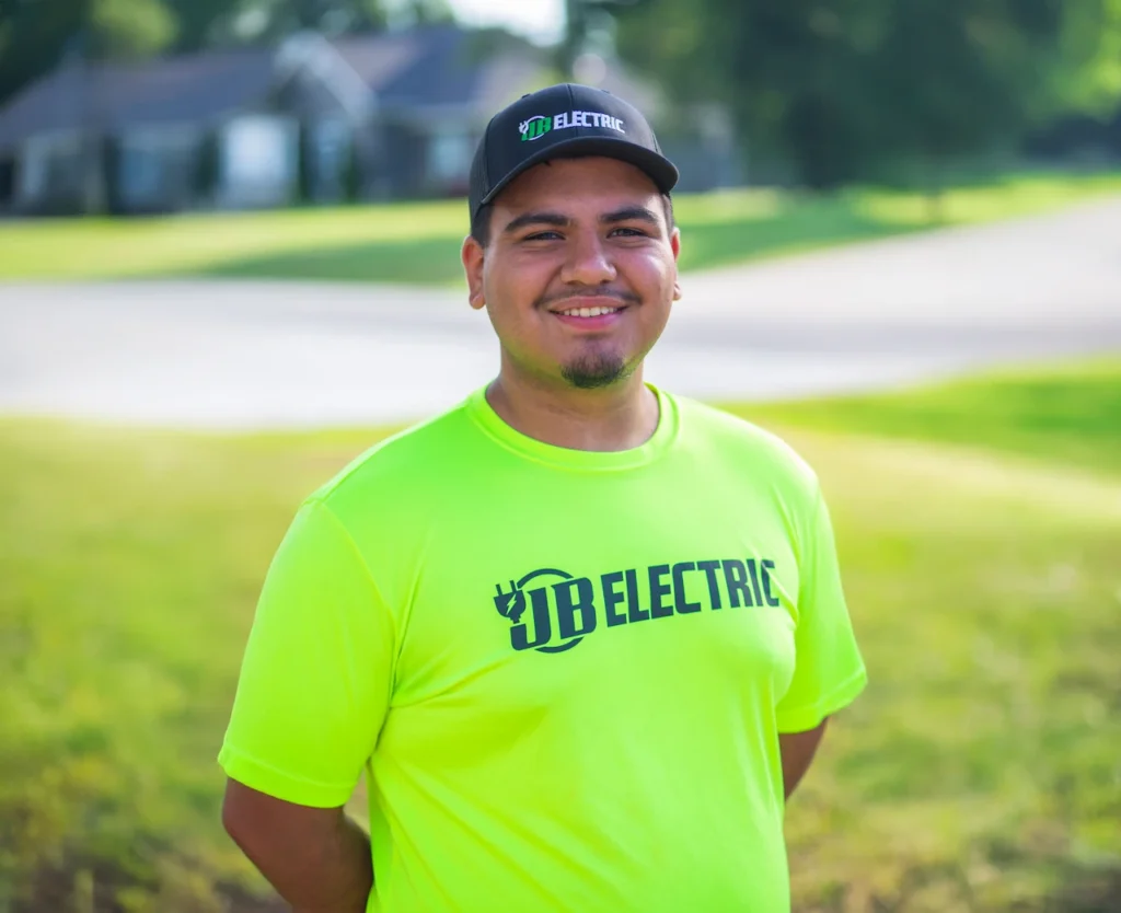 Smiling man in JB Electric shirt outdoors.