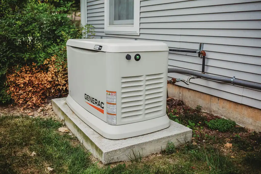 Home standby generator beside house wall.
