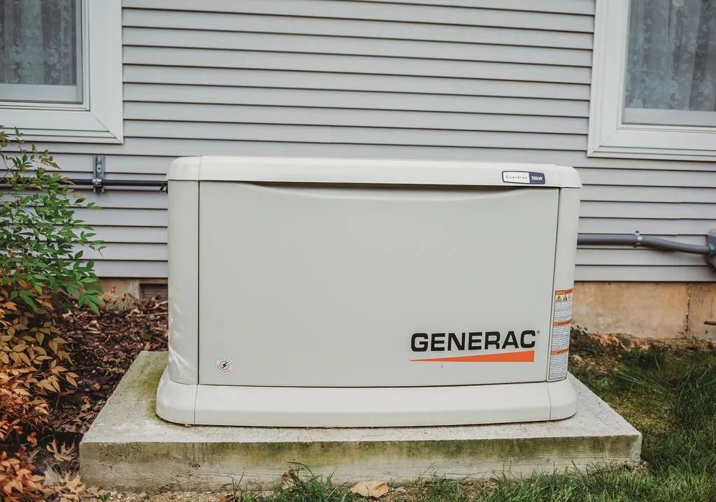 Outdoor Generac home backup generator beside house wall.