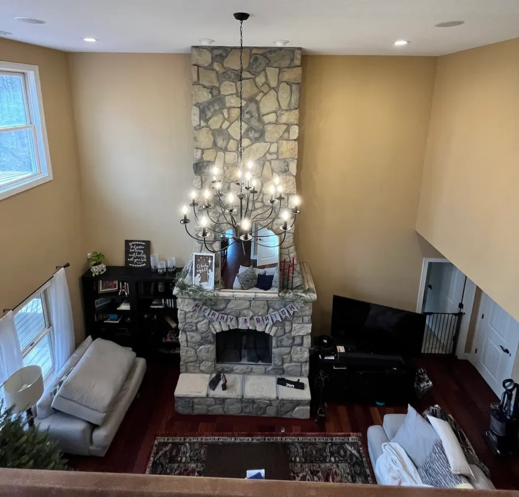 Spacious living room with stone fireplace and chandelier.