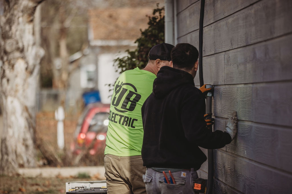 Electricians working on exterior house wall
