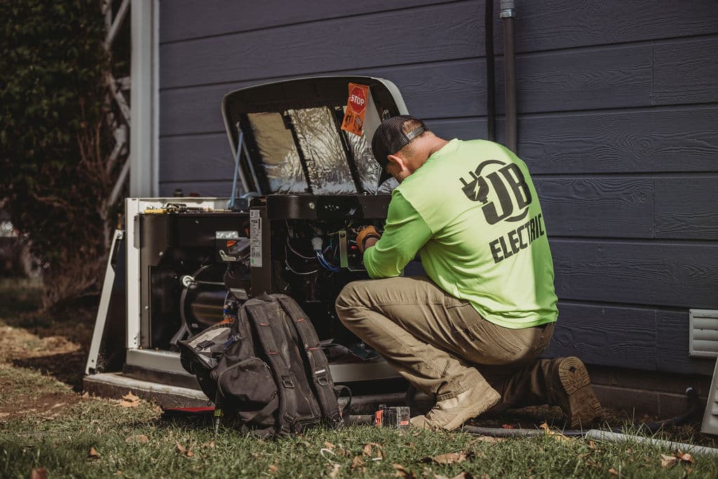 Electrician fixing outdoor generator beside house wall