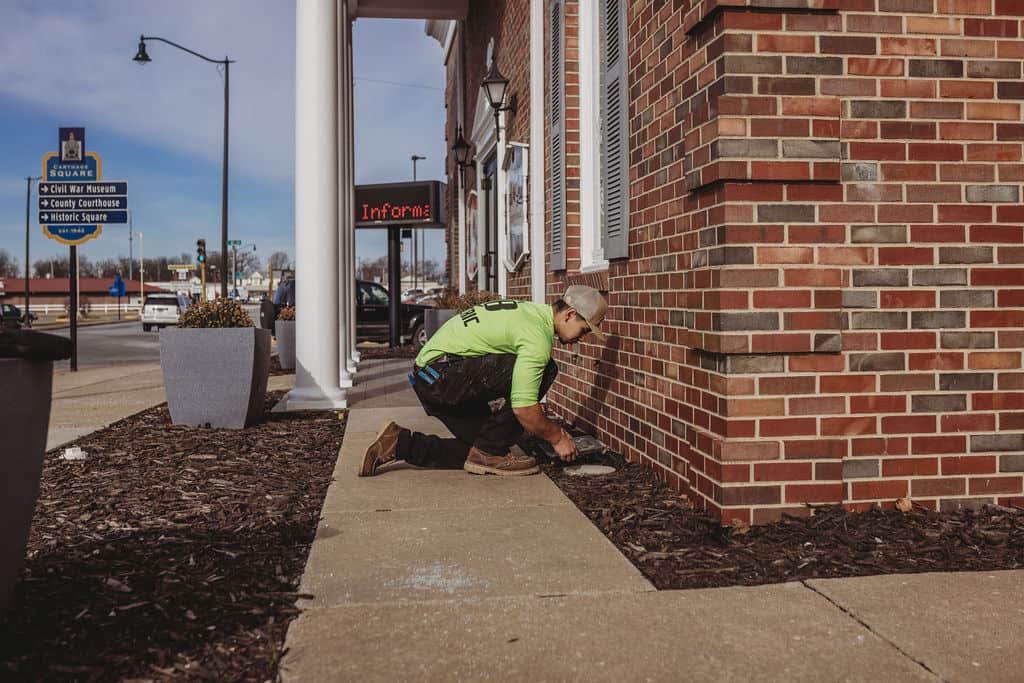 Worker maintaining brick building exterior sidewalk