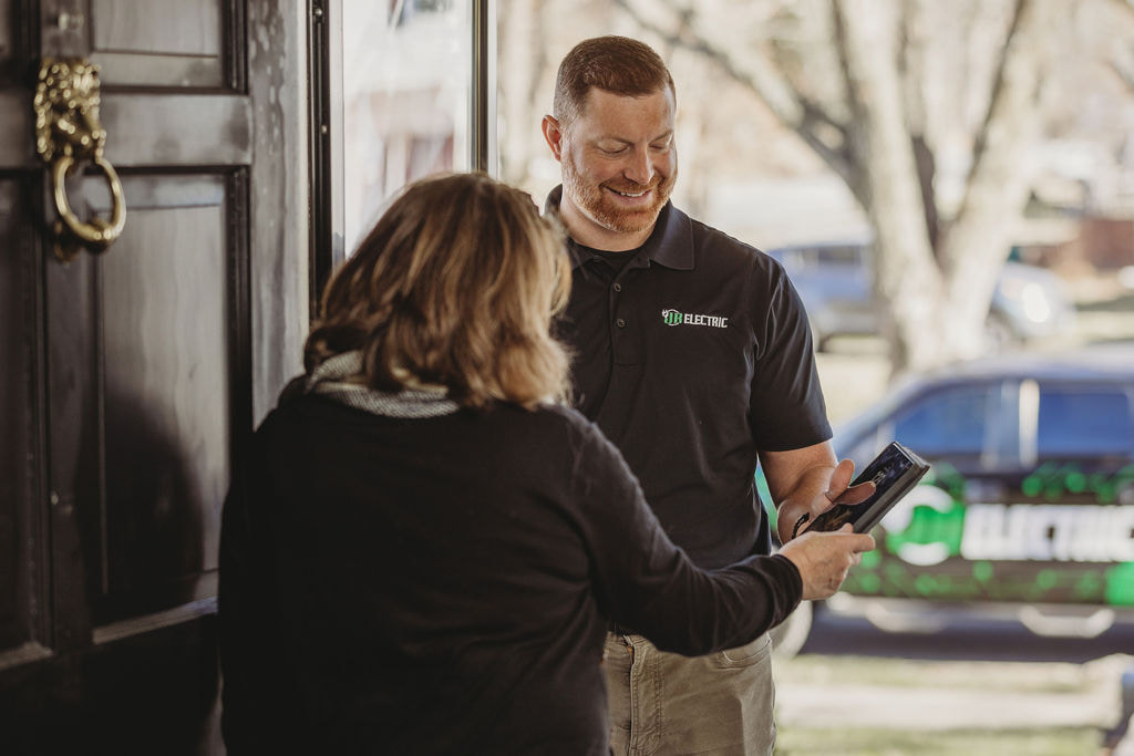 Electrician assisting customer at home door.
