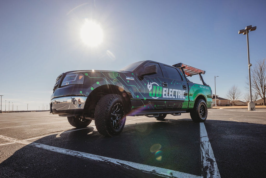 Electric service truck parked under sunny sky.