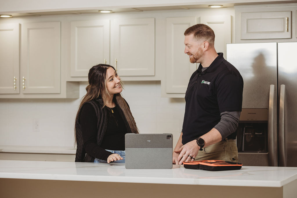 Man and woman talking in kitchen with tablet.