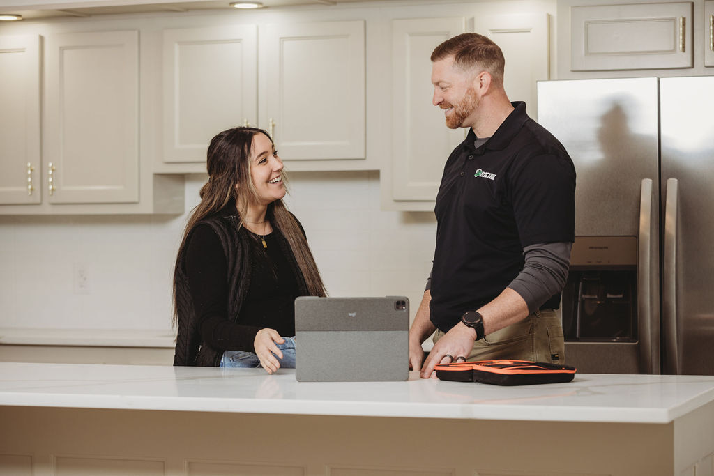 Smiling people talking in modern kitchen with laptop.