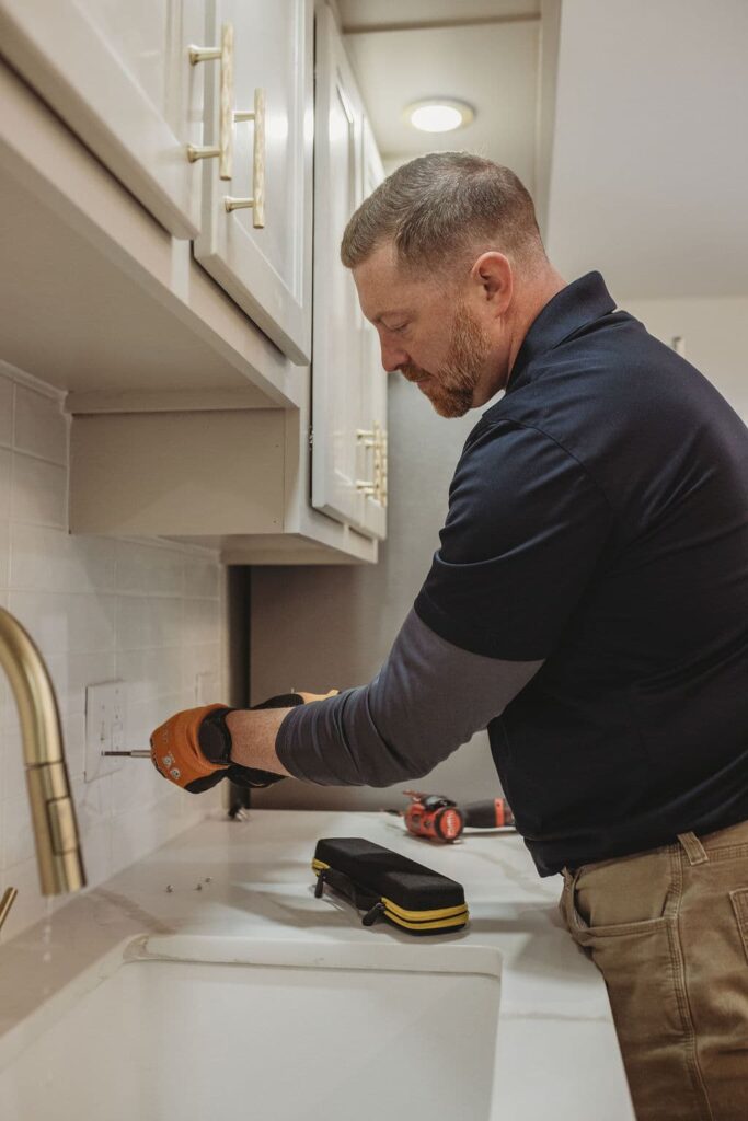 Person installing kitchen cabinet handles.