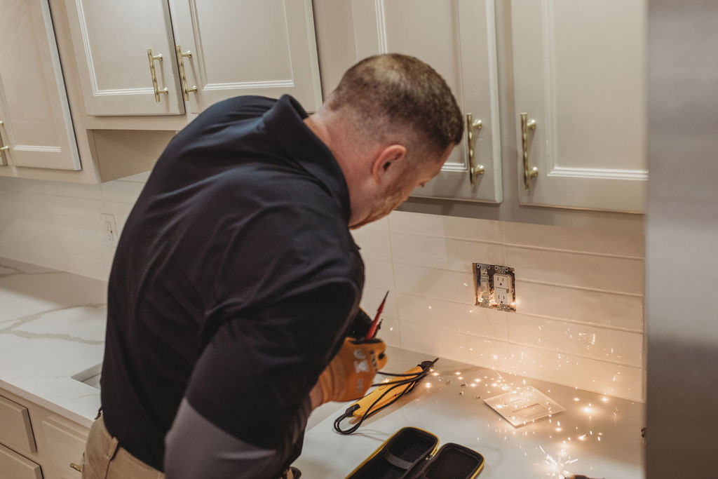Electrician working with sparks in kitchen outlet.