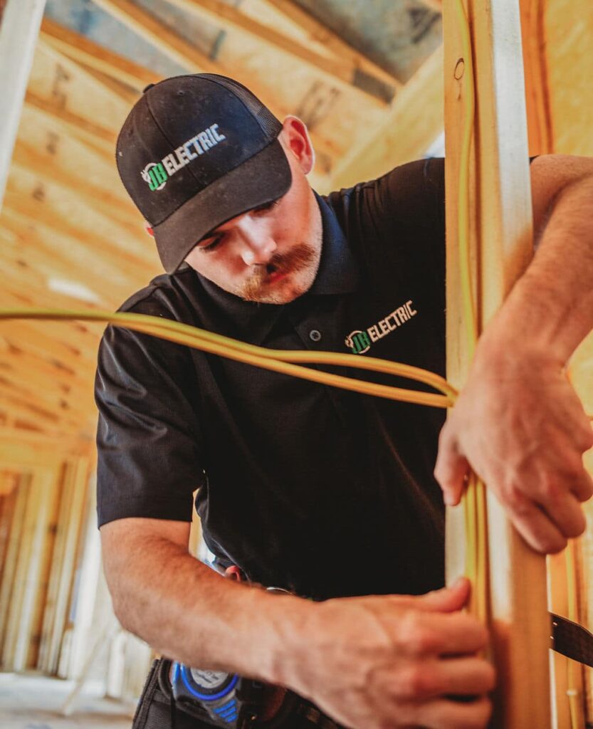 Electrician installing wiring in wooden frame.